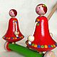 Two cheerful girls in bright red dresses dance and whirl when driving! Wooden toy - wooden gurney. Shop wooden toys teething toy.
